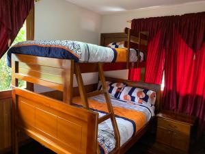 MacasにあるMY HOUSE IN MACAS, MIRADOR AL UPANOの赤いカーテンが備わるドミトリールームの二段ベッド2台分です。
