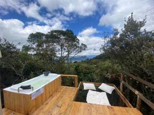 a hot tub on a wooden deck with two chairs at Cumbre Glamp in Tocancipá