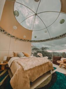 um quarto com uma cama grande e uma janela grande em Cumbre Glamp em Tocancipá