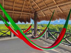 a pair of hammocks hanging from a thatched roof at Hotel Jaiba Mahahual - Adults Only in Mahahual