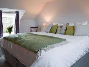 a large white bed with a green blanket on it at Rowanlea in Muthill