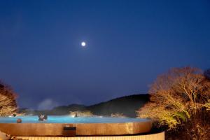 Una piscina de agua azul por la noche con la luna en Ecoland Hotel en Jeju