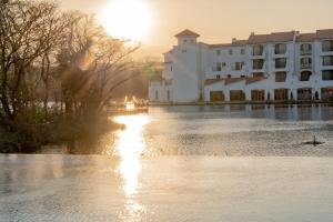 a building on a river with the sun setting behind it at Ecoland Hotel in Jeju