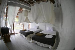 two beds in a room with white curtains at La Belle Hollow Trees in Katiet