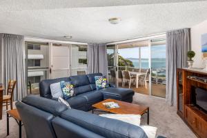 a living room with a blue couch and a television at Birdseye View Apartment at Nelson Bay in Nelson Bay