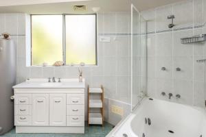 a white bathroom with a tub and a sink and a bath tubermott at Birdseye View Apartment at Nelson Bay in Nelson Bay