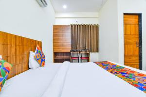 een slaapkamer met een groot bed en een houten hoofdeinde bij FabHotel 44 The M'Bience in Indore