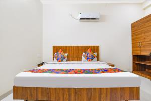een slaapkamer met een groot bed met een houten hoofdeinde bij FabHotel 44 The M'Bience in Indore