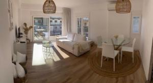 ein Wohnzimmer mit einem weißen Sofa und einem Glastisch in der Unterkunft Appartement boho chic près de la plage in Cambrils