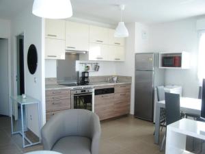 a kitchen with white cabinets and a silver refrigerator at Appartement Moderne avec Terrasse, Parking et Clim au Lavandou - 4 Couchages - FR-1-251-122 in Le Lavandou