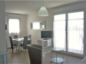 a dining room with a table with chairs and a television at Appartement Moderne avec Terrasse, Parking et Clim au Lavandou - 4 Couchages - FR-1-251-122 in Le Lavandou