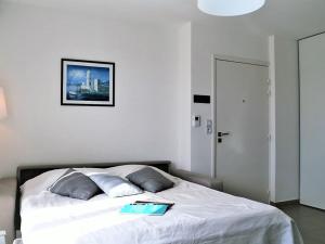 a bedroom with a white bed with a book on it at Appartement Moderne avec Terrasse, Parking et Clim au Lavandou - 4 Couchages - FR-1-251-122 in Le Lavandou