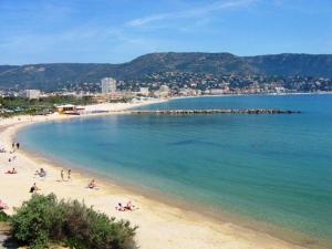a beach with people laying on the sand and the water at Appartement Moderne avec Terrasse, Parking et Clim au Lavandou - 4 Couchages - FR-1-251-122 in Le Lavandou