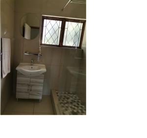 uma casa de banho com um lavatório, um chuveiro e um espelho. em Pumula Holiday Home em Hibberdene