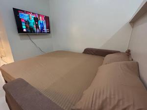 a bedroom with a bed and a flat screen tv at Sweden's Tiny Home, Studio Unit Condo in Manila