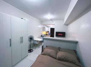 Sweden's Tiny Home, Studio Unit Condo في مانيلا: غرفة نوم مع سرير ومكتب مع تلفزيون
