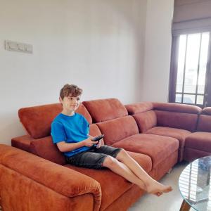 a young boy sitting on a couch holding a remote at Pensive Villa in Nuwara Eliya