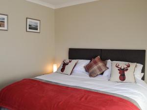 a bed with a red blanket and pillows on it at Glencairn Rd, in Langbank