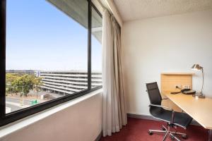 ein Büro mit einem Schreibtisch und einem großen Fenster in der Unterkunft Holiday Inn Melbourne Airport, an IHG Hotel in Melbourne