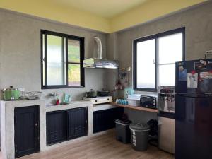 a kitchen with a black refrigerator and two windows at 初衷民宿 臺東縣民宿1466號 in Taitung City
