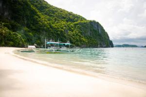 a boat sitting on the shore of a beach at The Funny Lion - El Nido in El Nido