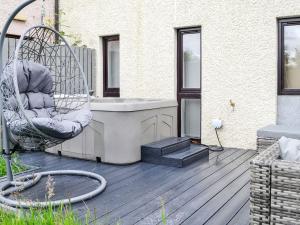 un porche con bañera y una silla en la cubierta en 3 Ladyknowe - Uk39969, en Moffat