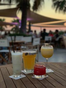 three glasses of drinks sitting on a wooden table at Horizon Pissouri Bay 1 bedroom apartment with communal pool in Pissouri