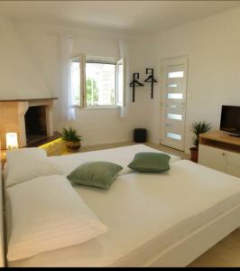 duże białe łóżko w pokoju z kominkiem w obiekcie APARTMENTS LUMA 1 w Hvarze