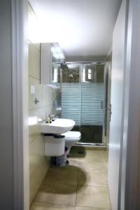a white bathroom with a sink and a mirror at Ourania Apartment in Drama