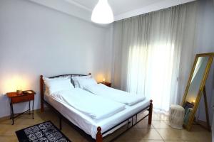 Schlafzimmer mit einem Bett mit weißer Bettwäsche und einem Fenster in der Unterkunft Ourania Apartment in Drama