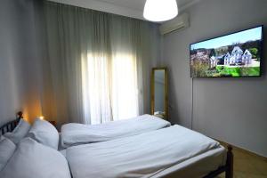 a bedroom with two beds and a tv on the wall at Ourania Apartment in Drama