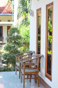 - deux chaises en bois assises sur la terrasse couverte d'une maison dans l'établissement Maja House Penida, à Nusa Penida