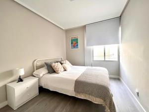 a white bedroom with a bed and a window at Housingleon La Paloma in León