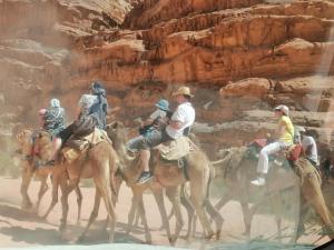 a group of people riding on camels in the desert at Lukasa camp Wadi Rum in Disah