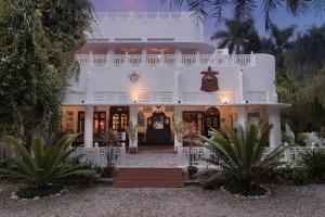 a large white house with palm trees in front of it at Jaagir Manor, Dudhwa - IHCL SeleQtions in Paliā Kalān