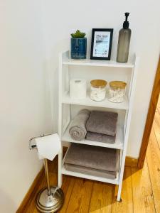 uma prateleira branca com toalhas e um candeeiro num quarto em The Annexe at Yew Tree House em Canterbury