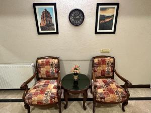 dwa krzesła i stół z zegarem na ścianie w obiekcie White House Cottages w mieście Murree