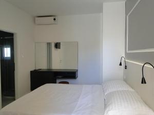 1 dormitorio con cama blanca y espejo en Rooms Tepli Bok, en Primošten