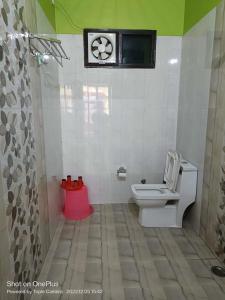 La salle de bains est pourvue de toilettes et d'une horloge murale. dans l'établissement Rudraksha Hotel & Restaurant By WB Inn, à Rāmnagar