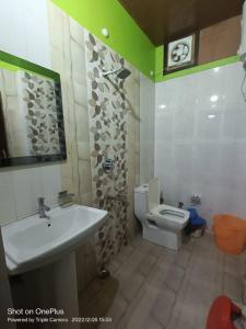 La salle de bains est pourvue d'un lavabo et de toilettes. dans l'établissement Rudraksha Hotel & Restaurant By WB Inn, à Rāmnagar