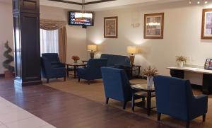 - une salle d'attente avec des tables et des chaises bleues et une télévision dans l'établissement Red Roof Inn & Suites Longview, à Longview