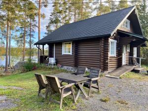 a cabin with a table and chairs in front of it at Elämyksellinen huvila Tuurujärven rannalla. in Ulvila