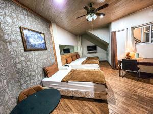 three beds in a room with a ceiling fan at Hotel Urban in Baguio