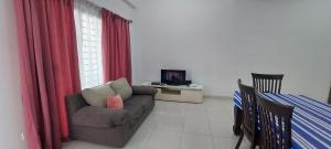 Hud Hud Homestay في Bandar Puncak Alam: غرفة معيشة بها أريكة وتلفزيون