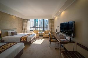 a hotel room with two beds and a flat screen tv at Gloucester Luk Kwok Hong Kong in Hong Kong