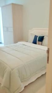 uma grande cama branca num quarto com uma janela em Benson Tower Surabaya Apartment 2BR by Le Ciel Hospitality em Lontar