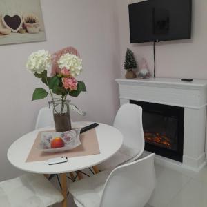 a white dining room with a table with flowers and a fireplace at Park Apartment in Niksic in Nikšić
