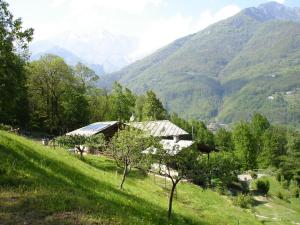 a house on a hill with mountains in the background at Joy Center - Casa e Appartamenti Vacanza in Val Pellice in Villar Pellice