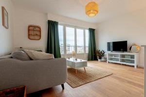 a living room with a couch and a tv at Le Jouvence Cozy - Confort - Zen - Parking gratuit in Dijon