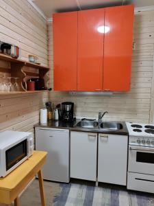 una cocina con electrodomésticos blancos y armarios naranjas en Guesthouse Pekkala, en Rovaniemi